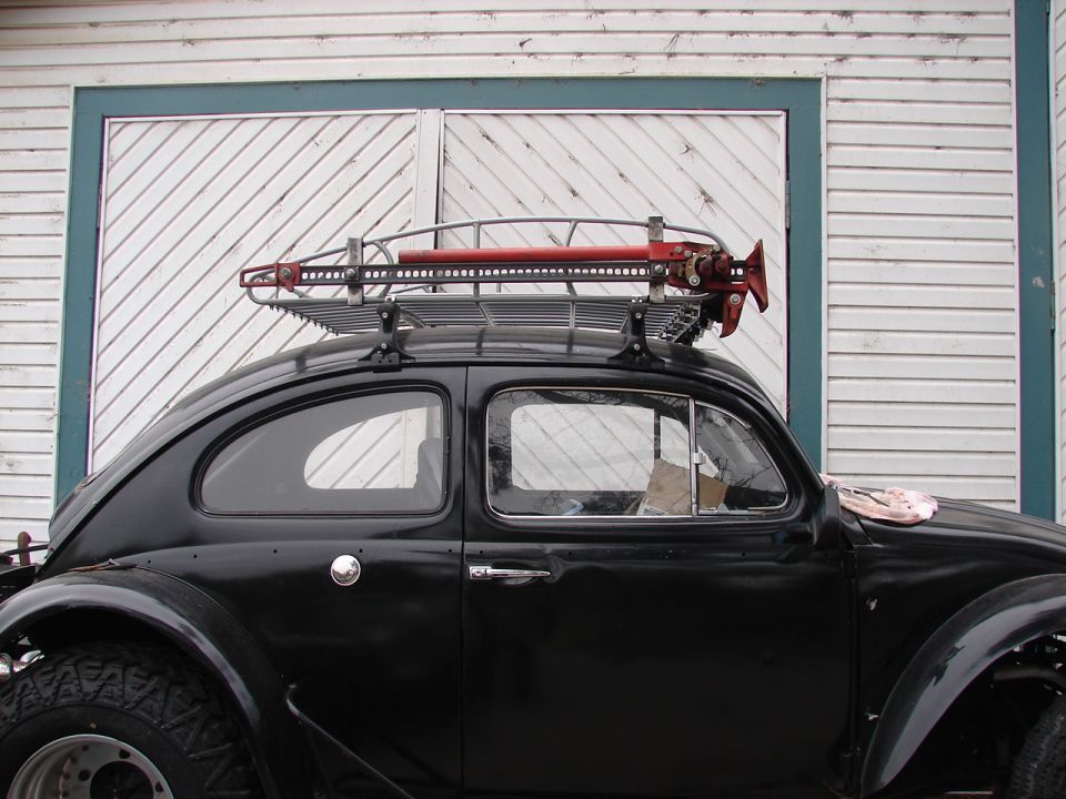Black 1964 Volkswagen Beetle side view with roof rack and red Hi-Lift jack