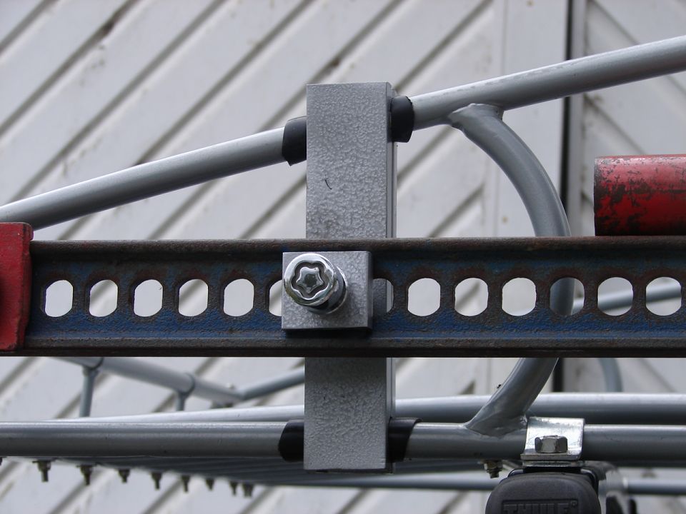 Close-up of a metal bracket with a star-shaped bolt head and perforated metal strip