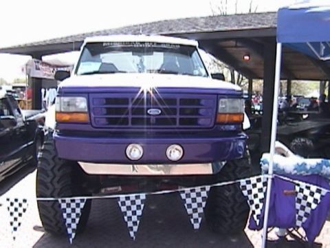 1995 Ford Bronco - A lifted Ford Bronco with a purple grille and large tires is parked outdoors.
