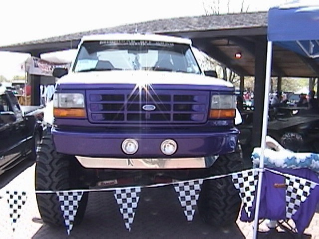 Purple Ford Bronco with large tires and chrome bumper, seen from the front