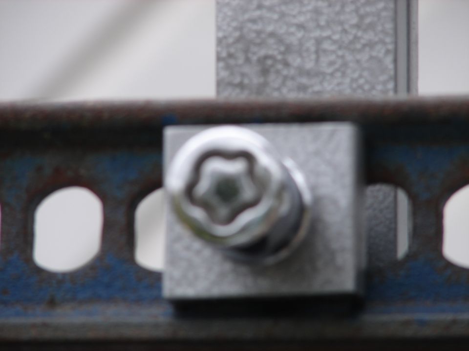 Close-up of a star-shaped bolt head on a metal bracket with holes