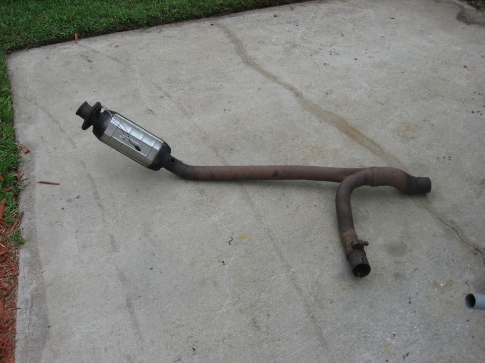 Exhaust pipe and catalytic converter removed from a vehicle, lying on concrete