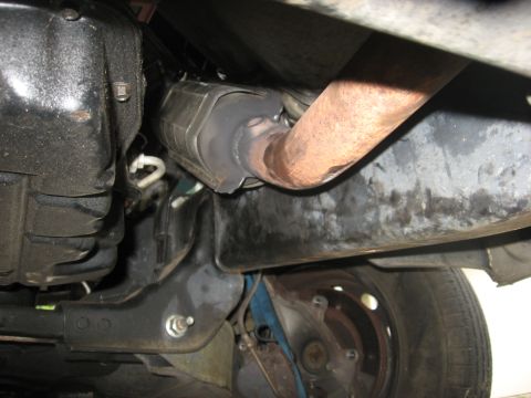 1994 Ford Bronco - Underside view of a 1994 Ford Bronco's exhaust system, showing the catalytic converter and rusted pipe.