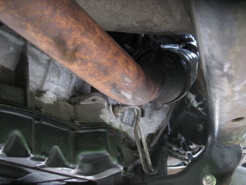 1994 Ford Bronco - Underside view of a vehicle's exhaust pipe and catalytic converter, showing signs of rust and wear.