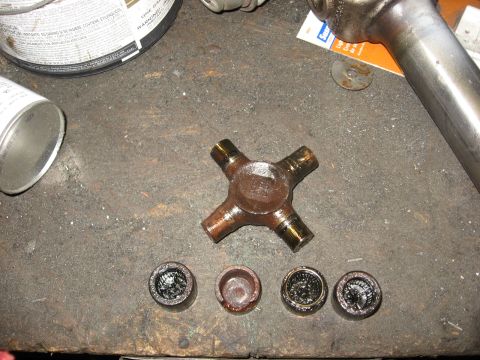 1994 Ford Bronco - A U-joint cross and its bearing cups are laid out on a workbench, possibly for replacement.