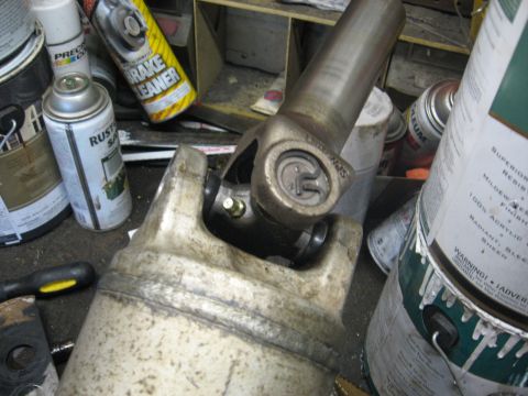 1994 Ford Bronco - A close-up view of a driveshaft U-joint assembly, with various automotive maintenance products in the background.