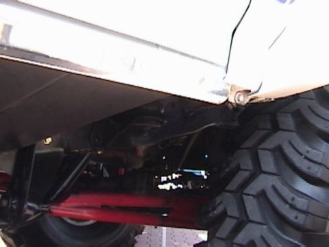 1995 Ford Bronco - Undercarriage view showing a large tire and suspension parts of a modified vehicle.