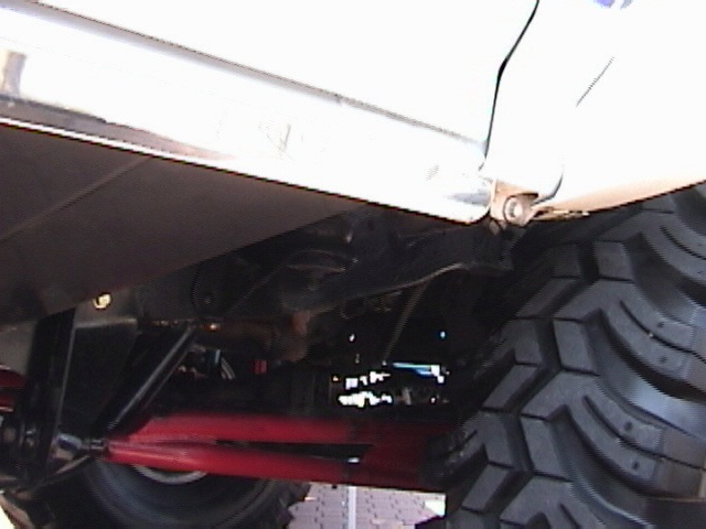 Close-up of a large off-road tire and vehicle undercarriage with red suspension components
