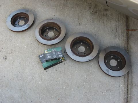 1994 Ford Bronco - New brake rotors and pads laid out on concrete, ready for installation.