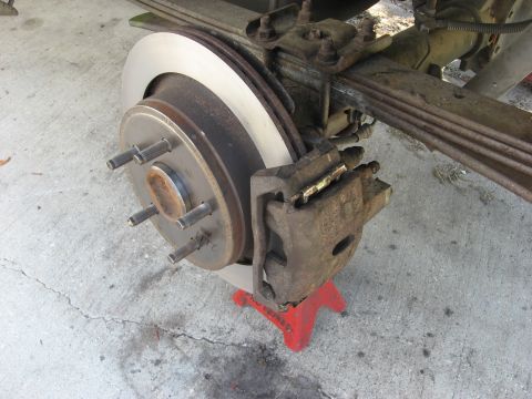 1994 Ford Bronco - Close-up of a vehicle's rear brake system, including the caliper, rotor, and suspension components.