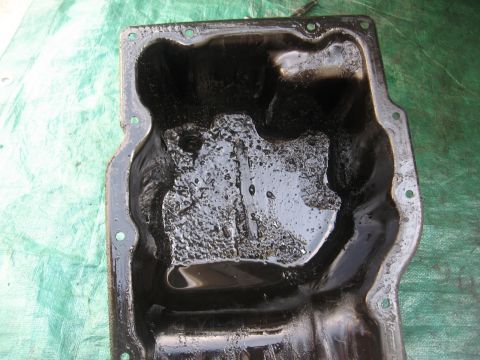 1994 Ford Bronco - This oil pan is filled with thick sludge and old oil, indicating potential engine issues.