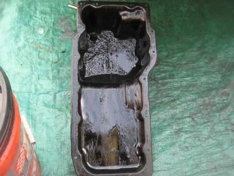 1994 Ford Bronco - This is an oil pan with sludge inside, placed on a green tarp.