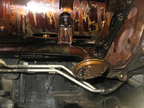1994 Ford Bronco - Close-up view of an engine's oil pan and pickup tube, indicating potential maintenance or repair needs.
