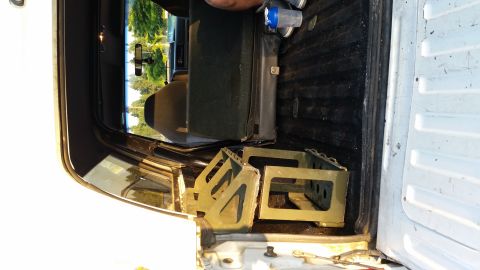 1993 Ford Bronco - Two metal battery boxes and a speaker are stored in the bed of a truck.