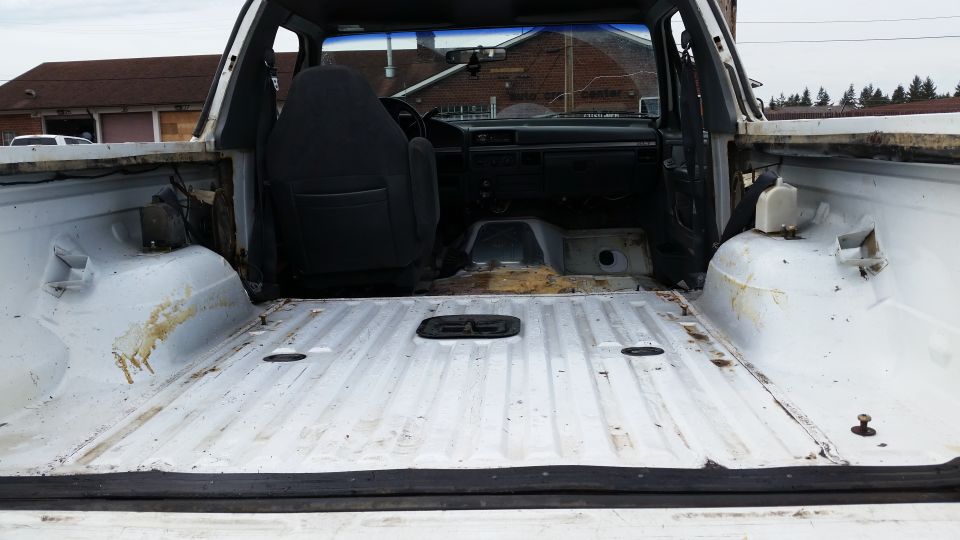 White pickup truck bed interior, showing worn seats and dashboard. Visible Supermotors.net logo
