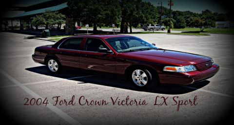 2004 Ford Crown Victoria - Stylized, vignetted three-quarter front view of a dark red Ford Crown Victoria sedan parked in an empty lot, wearing bright five-spoke allo…