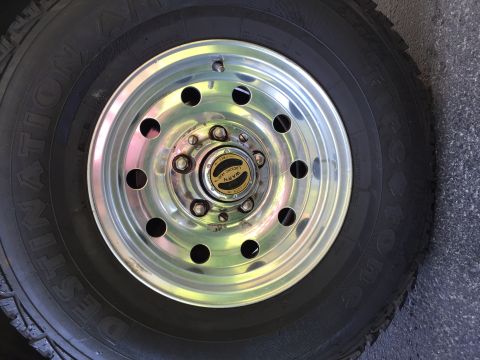 1994 Ford Bronco - A close-up view of a vehicle's wheel and tire, a chrome rim and a manually locking hub.