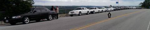 2000 Mercury Grand Marquis - Multiple Mercury Grand Marquis sedans are lined up along a scenic road, with a black one in the foreground.