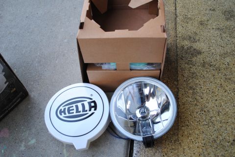 1986 Ford Bronco - Hella fog lights and their original packaging are displayed on a concrete surface.