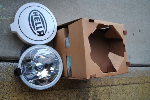 1986 Ford Bronco - A pair of Hella fog lights are shown next to their open shipping box.