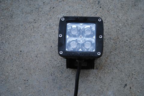 1986 Ford Bronco - A single black Rigid Industries LED light is shown against a textured concrete background.
