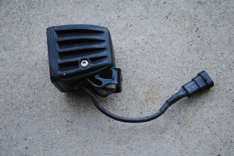 1986 Ford Bronco - A black LED light bar with its wiring and connector is shown against a concrete surface.
