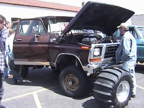 1995 Ford Bronco - This lifted Ford pickup truck, likely a 1979 model, is displayed with its hood open and massive tires.