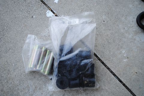 1986 Ford Bronco - Unidentified suspension bushings and hardware are shown packaged on a concrete surface.