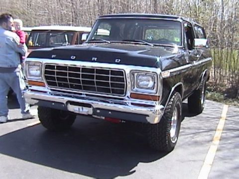 1995 Ford Bronco - This black Ford Bronco is parked outside with another vehicle in the background.