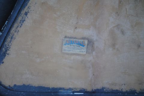 1986 Ford Bronco - A close-up view shows a faded label with blue and orange text that reads "AUTOBAB Off Road Trucks" affixed to a textured, tan surface.