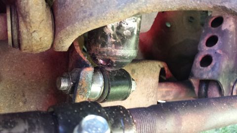1995 Ford Bronco - A close-up view of a suspension component, likely a sway bar link, with black rubber bushings and silver metal hardware. The surrounding fr…