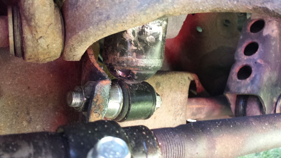 Close-up of vehicle suspension part with black bushings and metal hardware.