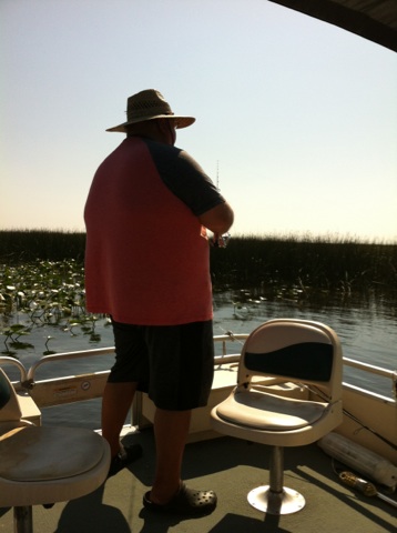 2007 Ford F-250 - A person wearing a straw hat and a pink and gray shirt is fishing from a boat on a calm body of water. The boat has two seats and is surrou…