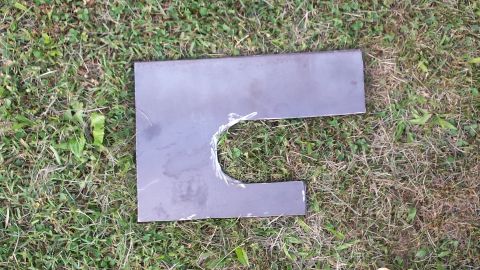 Cut metal part with a U-shaped notch on grass