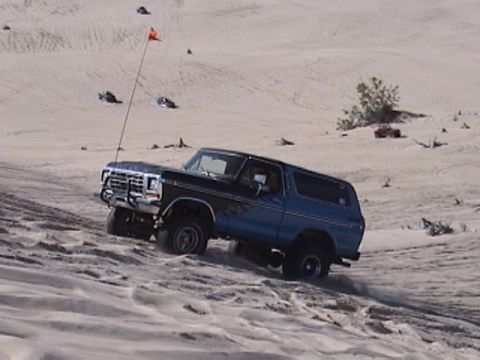 1995 Ford Bronco - This Ford Bronco is navigating a sandy terrain, kicking up dust as it goes.