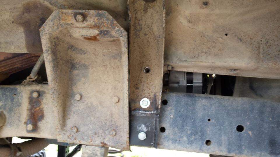 Close-up of rusty vehicle frame with welded bracket and bolts