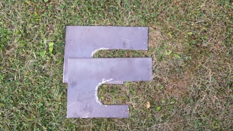 Two metal pieces shaped like the letter E on grass.