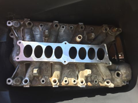1996 Ford Bronco - This is a close-up, overhead view of a used aluminum intake manifold, likely for a Ford vehicle, with a gasket in place. The manifold is gr…