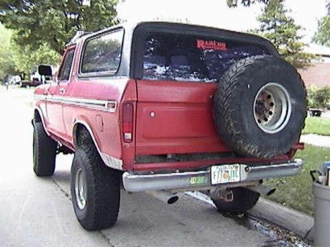 1995 Ford Bronco - This red Ford Bronco, likely from the late 1970s, is viewed from the rear, showing its spare tire and a 'Rancho' sticker on the window.