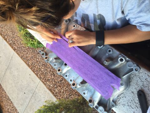 1996 Ford Bronco - A person is applying purple masking tape to a silver metal engine intake manifold. The manifold has several bolt holes and some stamped num…