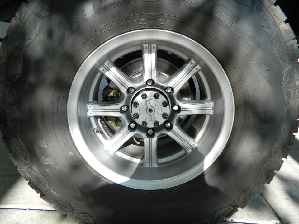 Close-up of a large off-road tire and silver wheel with visible brake components.