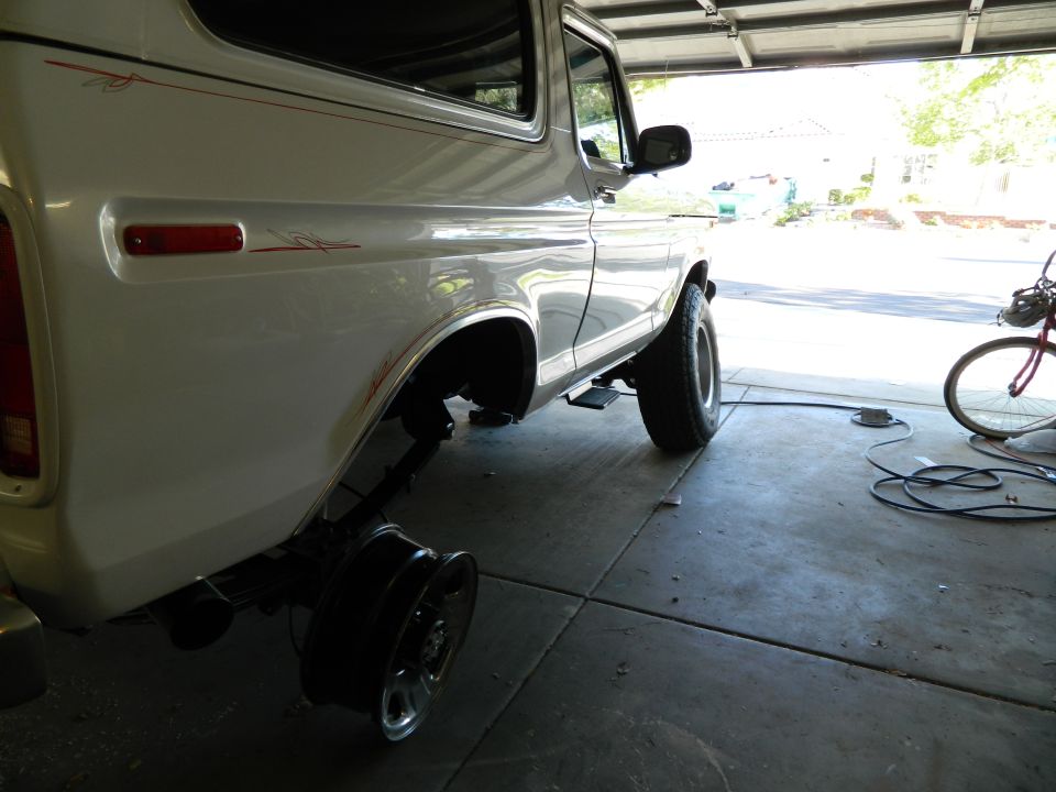 White Ford Bronco in garage, rear wheel removed.