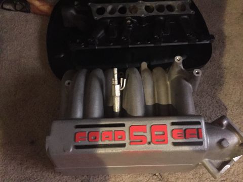 1996 Ford Bronco - A silver Ford 5.8 EFI intake manifold is shown, with the "FORD" and "5.8 EFI" text highlighted in red. The manifold is placed on a carpeted…