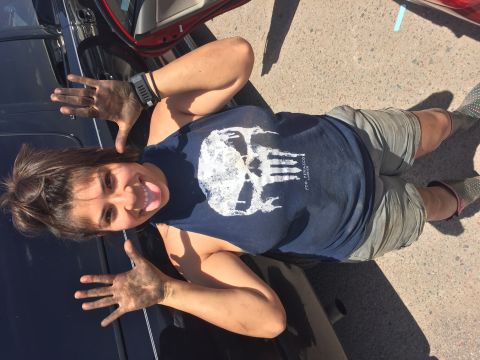 1996 Ford Bronco - A woman with dirty hands sticks her tongue out while posing next to a black vehicle. She is wearing a dark blue tank top with a white skull…