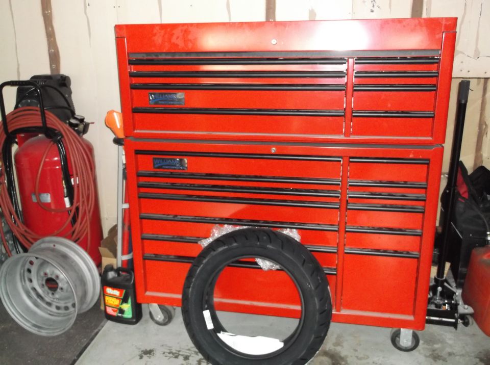 Red tool chest, air compressor, car wheels, and motorcycle tire.