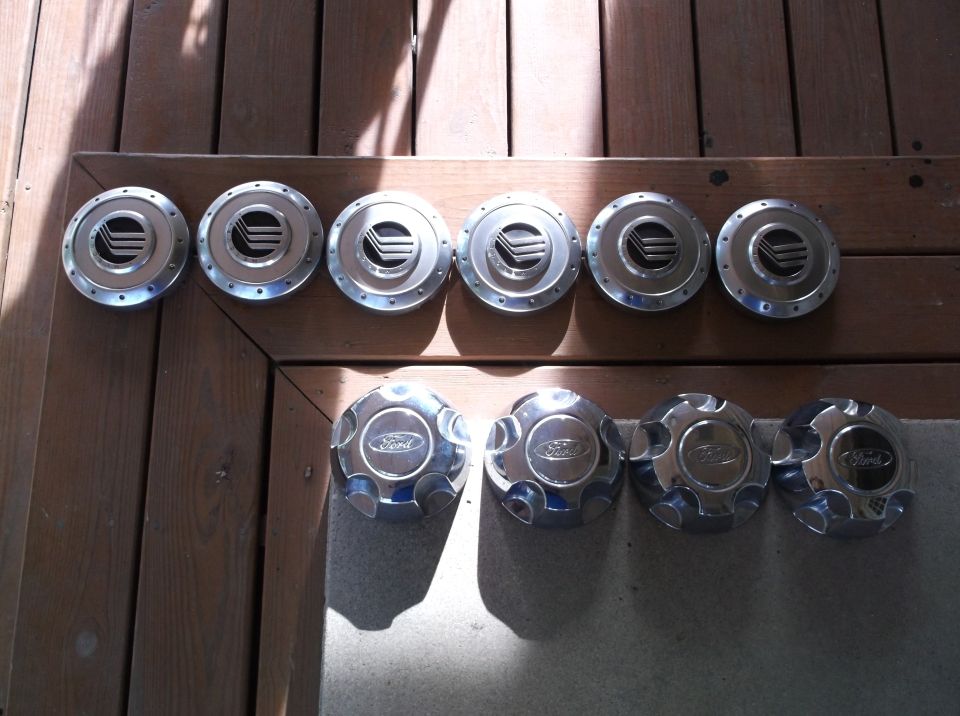Set of ten car hubcaps, five silver with black emblems and five chrome with Ford logos.