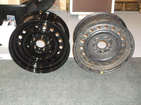 1999 Mercury Grand Marquis - Two steel wheels are shown, one is shiny black and appears new, while the other is dull gray and shows signs of wear and rust. They are pos…