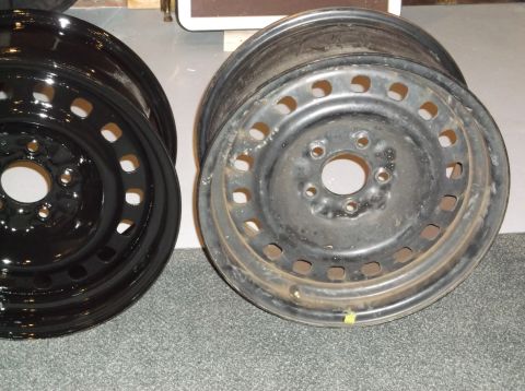 1999 Mercury Grand Marquis - Two steel wheels are shown, one is shiny black and the other is matte black with visible wear and rust. The wheels are positioned side-by-s…