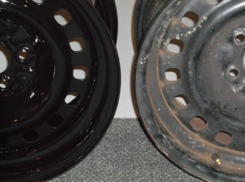 1999 Mercury Grand Marquis - A close-up side-by-side comparison of two black steel wheels. The wheel on the left appears to be newly painted and shiny, while the wheel…
