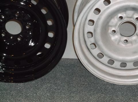 1999 Mercury Grand Marquis - Two steel wheels are shown, one painted glossy black and the other painted a matte silver primer. The wheels are positioned side-by-side on…
